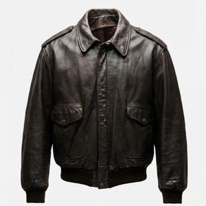 Puede incluir: Chaqueta bomber de cuero marrón con cuello, dos bolsillos delanteros y puños y dobladillo de canalé. La chaqueta tiene un diseño clásico y un aspecto vintage. La chaqueta es de talla mediana.