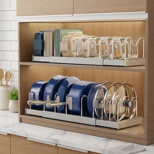May include: A kitchen cabinet with two shelves. The top shelf holds stacks of blue, green, and beige containers and clear glasses. The bottom shelf displays blue pots and clear lids, all neatly organized in metal racks.