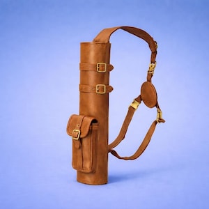 Puede incluir: Un carcaj de cuero marrón con una correa para el hombro y una pequeña bolsa. El carcaj tiene dos correas con hebilla y herrajes dorados. El fondo es de color azul claro liso.