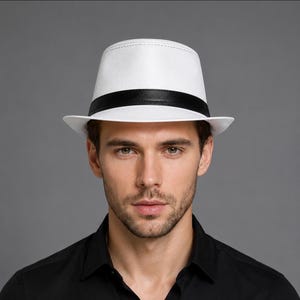 May include: A white fedora hat featuring a structured crown and a wide brim. The hat is accented with a smooth, solid black band encircling the base of the crown, providing a sharp contrast against the crisp white material of the hat body.