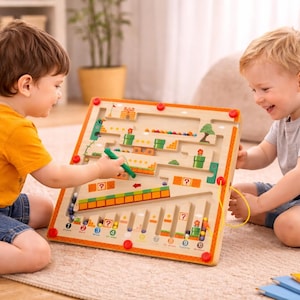 May include: Two young children playing with a wooden maze game. The game features a colorful design with various obstacles and a path for the included beads. The children are using a magnetic wand to guide the beads through the maze.
