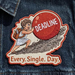 May include: Embroidered patch featuring a cartoon figure pushing a red sphere labeled "DEADLINE" up a rocky hill. The text "Every. Single. Day." is below the image. The patch has a cream-colored border and is set against a denim background.