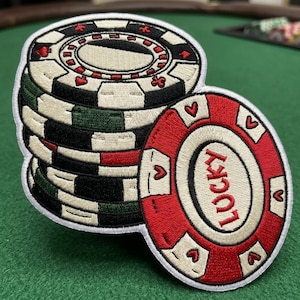May include: Embroidered patch featuring a stack of poker chips. The chips are white, black, red, and green, with heart, club, and diamond symbols. One chip is red with the word "LUCKY" and heart symbols.