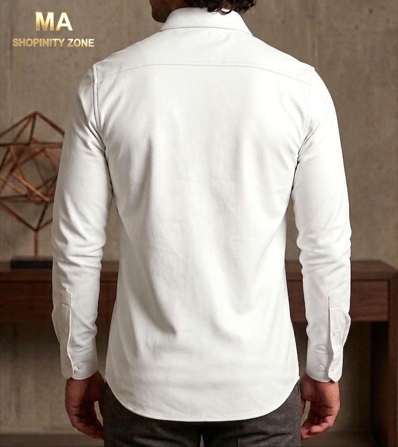 May include: A white long-sleeve button-down shirt. The shirt has a classic collar, buttoned cuffs, and a tailored fit. The text "MA SHOPINITY ZONE" is visible in the upper left corner.