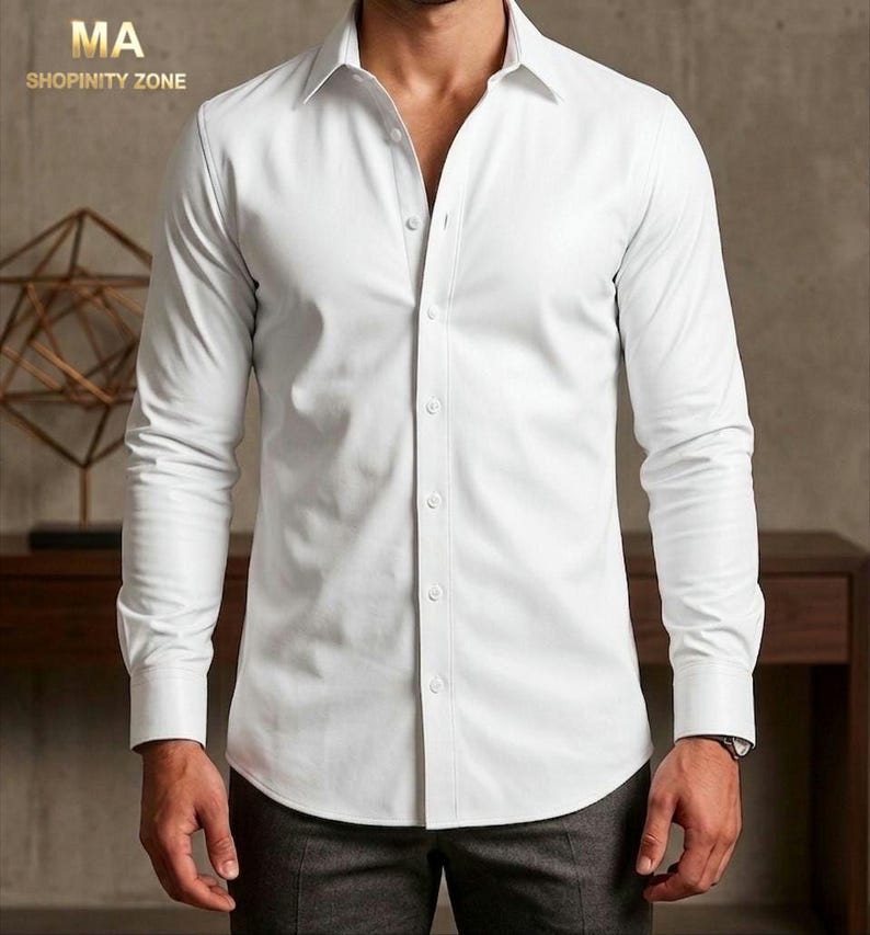 May include: A white button-down shirt with long sleeves. The shirt has a classic collar and is buttoned up the front. The image also shows the text "MA SHOPINITY ZONE" in the upper left corner.