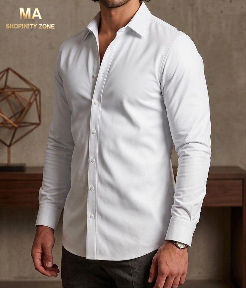 May include: A white button-down shirt with long sleeves. The shirt has a classic collar and is buttoned up the front. The image includes the text "MA SHOPINITY ZONE" in the upper left corner.