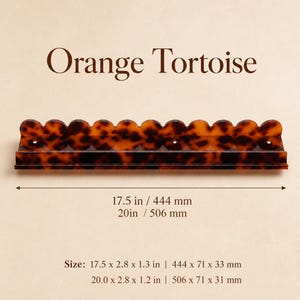 May include: An orange tortoise-shell shelf with a scalloped top edge. The shelf is 17.5 inches long and 2.8 inches wide. The text "Orange Tortoise" is above the shelf.