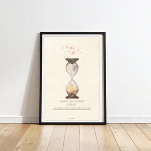 May include: Framed art print featuring an hourglass illustration with the text "Time is the Ultimate Luxury." The artwork has a neutral color palette with a black frame. Small pink bird silhouettes are above the hourglass.