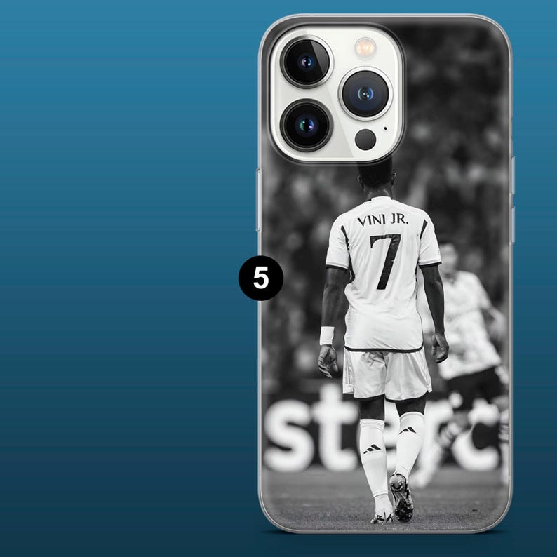 May include: A black and white phone case featuring a soccer player in a white jersey with the number 7 and the name VINI JR. The player is walking away from the camera on a green field.