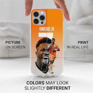 May include: A clear phone case featuring a split design with a portrait of Vinicius Jr. The left side shows a close-up of his face, while the right side displays a full-body image of him in an orange uniform. The background is orange with the text "VINICIUS JR".