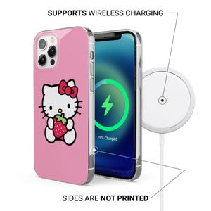 May include: Pink phone case featuring a Hello Kitty design holding a strawberry. The phone case is next to a phone displaying a charging symbol. The text "SUPPORTS WIRELESS CHARGING" and "SIDES ARE NOT PRINTED" are visible.