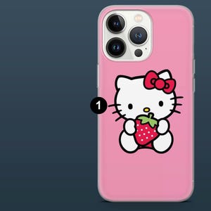 May include: Pink phone case featuring a Hello Kitty design. The white cartoon cat has a red bow and is holding a strawberry. The case has a clear border and covers the phone's camera and buttons.