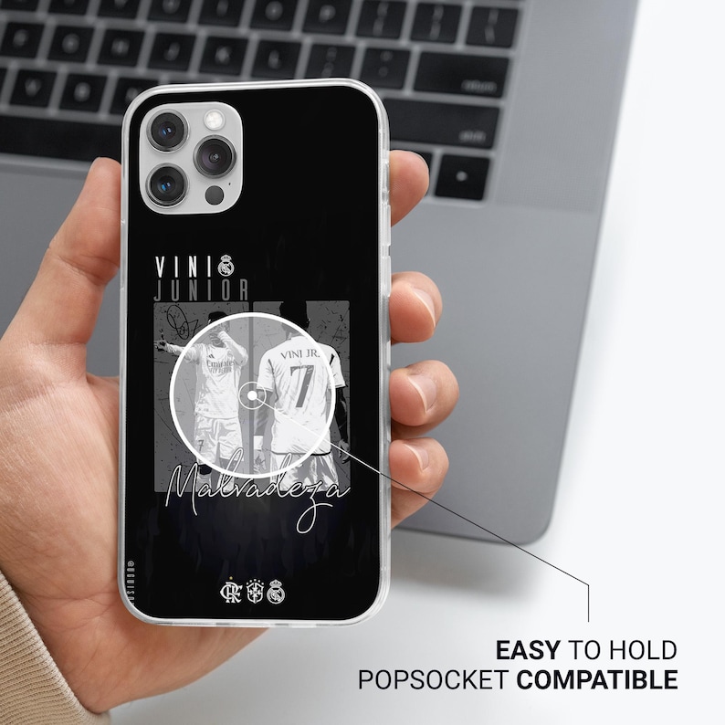 May include: Black phone case featuring a graphic of a soccer player in a white jersey with the number 7. The case has the text "VINI JR" and "Maldadeza" in white. The case is labeled "EASY TO HOLD POPSOCKET COMPATIBLE".