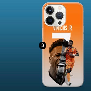 May include: Orange phone case featuring a graphic of soccer player Vinicius Jr. The design includes the player's name, jersey number 7, and a split image of his face and body in an orange uniform. The case has a clear border.