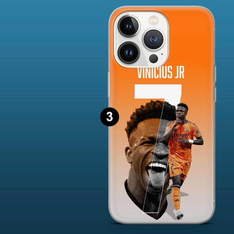 May include: Orange phone case featuring a graphic of soccer player Vinicius Jr. The design includes the player's name, jersey number 7, and a split image of his face and body in an orange uniform. The case has a clear border.