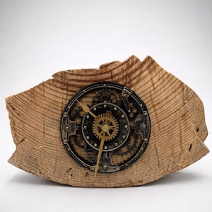 Può includere: Un orologio in stile steampunk con un design a ingranaggi, incastonato in una base di legno naturale. Il quadrante dell'orologio è nero e metallico, con ingranaggi e lancette color oro. La base in legno è marrone chiaro e ha un bordo naturale ruvido.