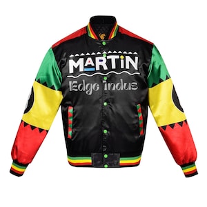 Può includere: Giacca bomber in raso nero con dettagli rossi, gialli e verdi. La giacca presenta la scritta "MARTIN" a blocchi bianchi sopra "Edge Indus". Le maniche hanno un motivo unico con un cerchio nero.