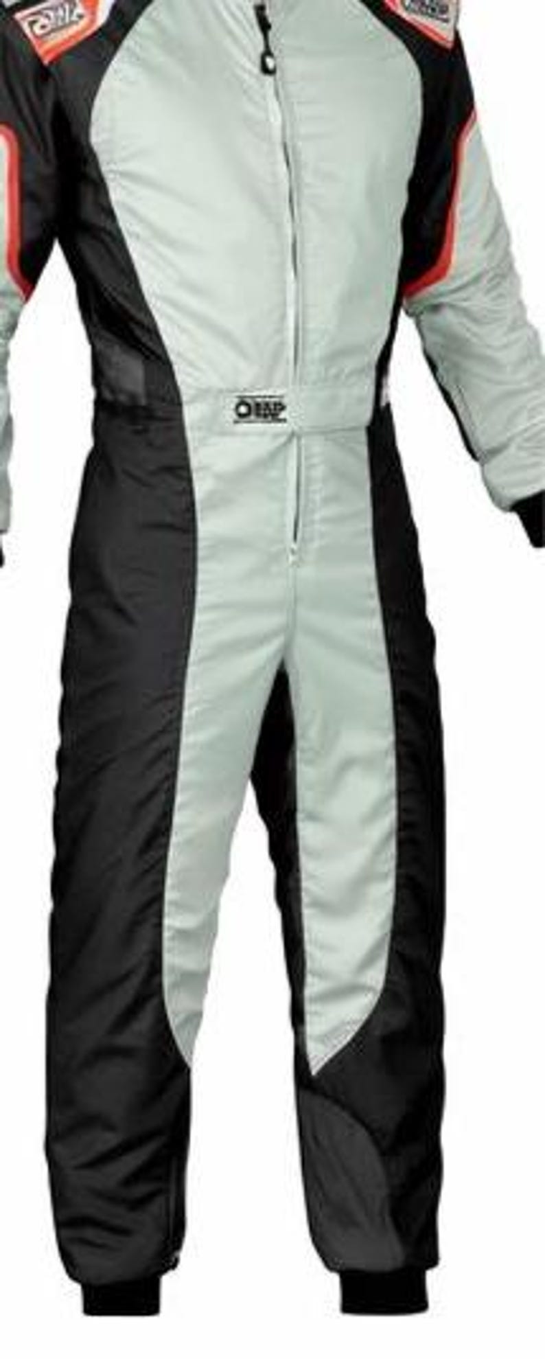 May include: A light gray and black racing suit featuring a central zipper closure, long sleeves with red accents, and the OMP logo printed on the chest and shoulder areas. The garment has a fitted silhouette with black side panels and cuffs.