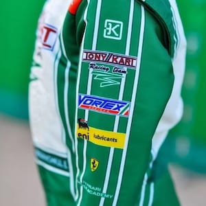 May include: Green and white racing suit with sponsor logos. The suit displays the "TONY KART Racing Team" logo, "VORTEX" logo, and "eni lubricants" logo. The Ferrari Academy logo is also visible.