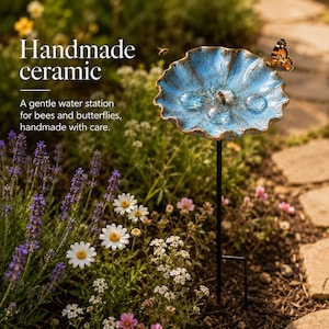 May include: A blue ceramic water station for pollinators featuring a scalloped, flower-like bowl with a speckled glaze finish. The bowl is mounted on a thin black metal stake. Text on the image reads: Handmade ceramic. A gentle water station for bees and butterflies, handmade with care.