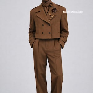 May include: A brown suit featuring a double-breasted jacket with black buttons, matching trousers, and a scarf. A rose-shaped brooch adorns the jacket. The outfit is completed with black shoes and sunglasses. The text "LuxuriousAuraStudio" is visible.