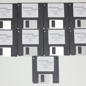 May include: A collection of black 3.5-inch floppy disks, each with a white label. The labels read "Modulation Station" along with additional text. The disks are arranged in a grid pattern, with one disk at the bottom.