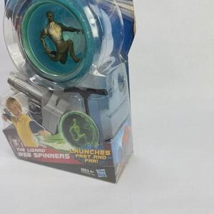 May include: A Spider-Man themed toy, featuring a clear plastic yo-yo with a teal interior and a figure of The Lizard. The packaging reads "The Lizard Web Spinners" and "Launches Fast and Far!"
