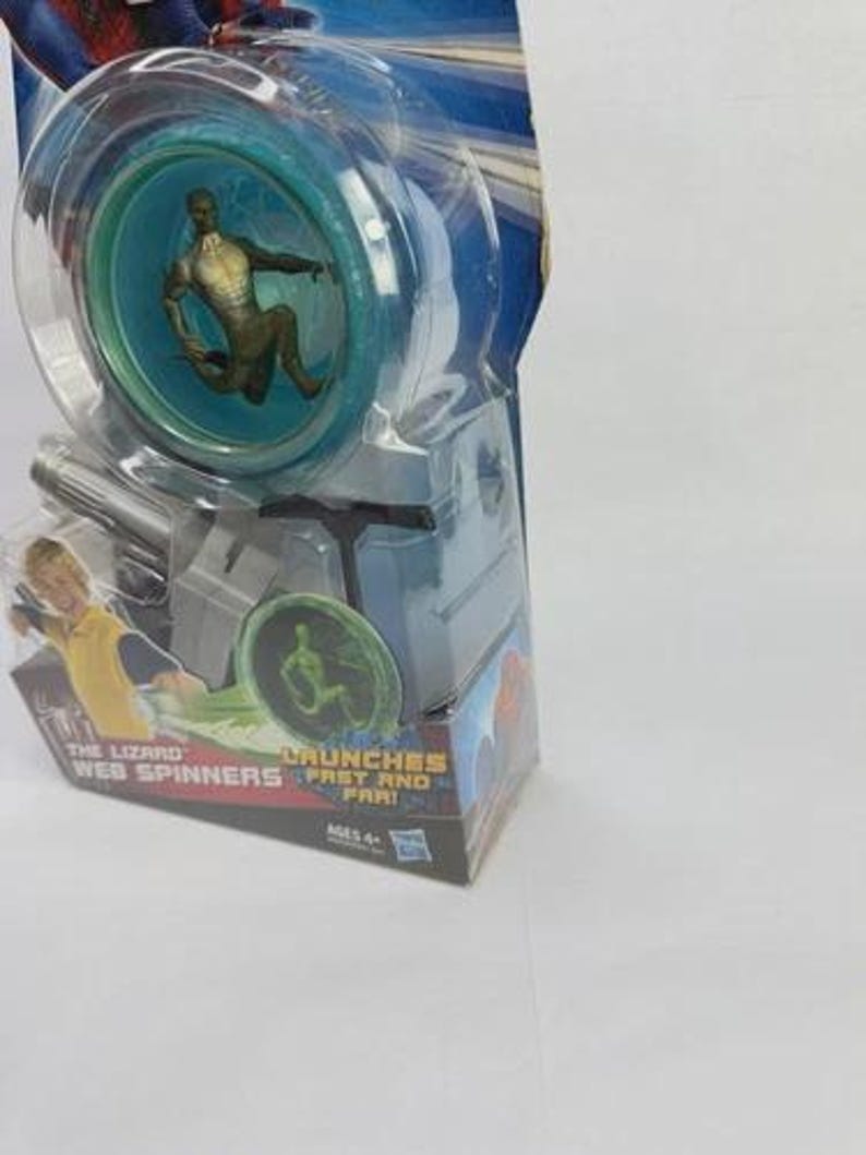 May include: A Spider-Man themed toy, featuring a clear plastic yo-yo with a teal interior and a figure of The Lizard. The packaging reads "The Lizard Web Spinners" and "Launches Fast and Far!"
