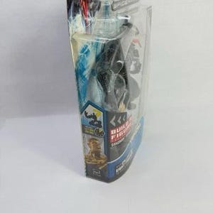 May include: A black Venom action figure in a clear plastic package. The packaging features a blue and white design with the words "Build Figure" and "Venom" printed on it. The figure is a collectible item.