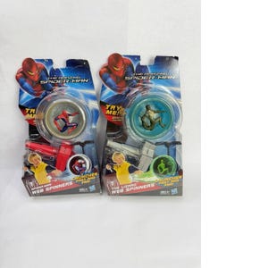 May include: Two Spider-Man Web Spinners toys in their original packaging. Each package features a clear plastic window showcasing the toy's design. The packaging includes the text "The Amazing Spider-Man" and "Web Spinners". One toy features Spider-Man, the other The Lizard.
