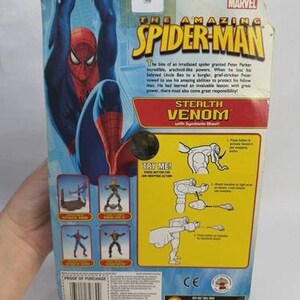 May include: The back of a Spider-Man action figure package. The package features a blue and red Spider-Man graphic, the text "The Amazing Spider-Man", and the words "Stealth Venom". The package also includes instructions and the Marvel logo.