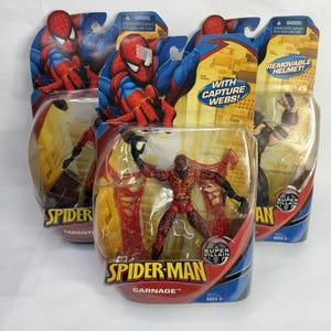 May include: Multiple Spider-Man action figures in their original packaging. The figures include Spider-Man and Carnage, with the packaging featuring vibrant colours and the words "With Capture Webs!" and "Removable Helmet!"