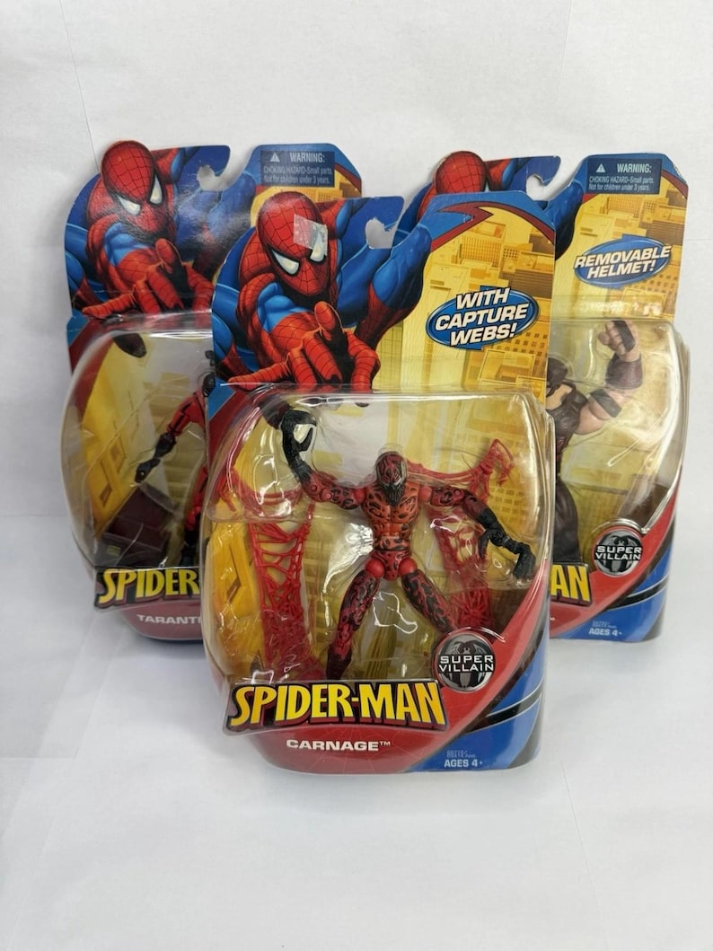 May include: Multiple Spider-Man action figures in their original packaging. The figures include Spider-Man and Carnage, with the packaging featuring vibrant colours and the words "With Capture Webs!" and "Removable Helmet!"