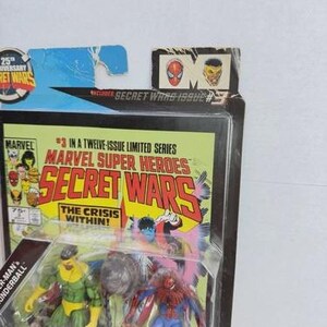 K&ouml;nnte beinhalten: Marvel Super Heroes Secret Wars Actionfiguren-Set. Die Verpackung enth&auml;lt ein Comic-Cover mit dem Text "Secret Wars" und "The Crisis Within!". Das Set enth&auml;lt Spider-Man und eine weitere Actionfigur. Die Verpackung enth&auml;lt auch den Text "25th Anniversary Secret Wars".