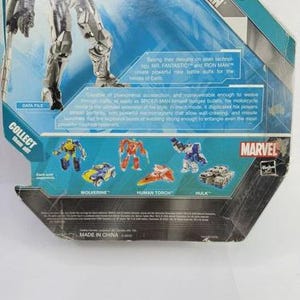 Puede incluir: Una figura de acci&oacute;n de Spider-Man de Marvel con un traje negro, con un fondo azul y blanco. El embalaje incluye texto sobre las habilidades del personaje y otros personajes de Marvel como Wolverine y Hulk.