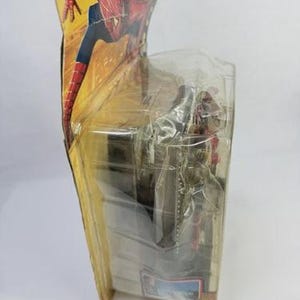 May include: A Spider-Man action figure in its original packaging. The packaging features a dynamic illustration of Spider-Man in a red and blue suit. The figure is visible through a clear plastic window, showcasing the character's pose and design.