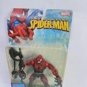 Puede incluir: Figura de acci&oacute;n de Toxin de la serie The Amazing Spider-Man. La figura es roja y negra, con un dise&ntilde;o de bestia simbionte. El embalaje incluye el logotipo de Marvel y la palabra "Toxin".