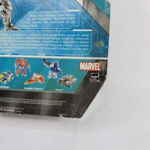 Puede incluir: Un paquete de figuras de acci&oacute;n parcialmente visible con el logotipo de Marvel y la palabra "MAN". El paquete tiene un dise&ntilde;o azul y verde azulado con texto que describe las habilidades del personaje. El paquete tambi&eacute;n muestra im&aacute;genes de otros personajes de Marvel.
