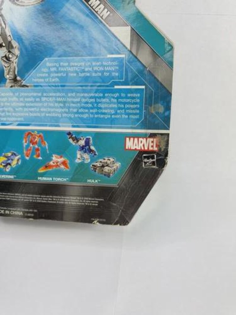 Puede incluir: Un paquete de figuras de acci&oacute;n parcialmente visible con el logotipo de Marvel y la palabra "MAN". El paquete tiene un dise&ntilde;o azul y verde azulado con texto que describe las habilidades del personaje. El paquete tambi&eacute;n muestra im&aacute;genes de otros personajes de Marvel.