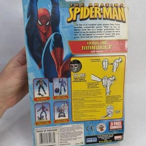 May include: The Amazing Spider-Man action figure packaging. The package features a large image of Spider-Man in a blue and red suit. The text "HOWLING MANWOLF" is visible, along with the Marvel logo.