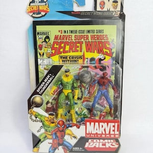 K&ouml;nnte beinhalten: Marvel Secret Wars Comic Packs Actionfiguren. Die Verpackung enth&auml;lt ein Comic-Cover mit dem Titel "Secret Wars" und dem Marvel-Logo. Die Figuren umfassen Spider-Man, Thunderball und andere Charaktere. Die Verpackung enth&auml;lt auch den Text "25th Anniversary".