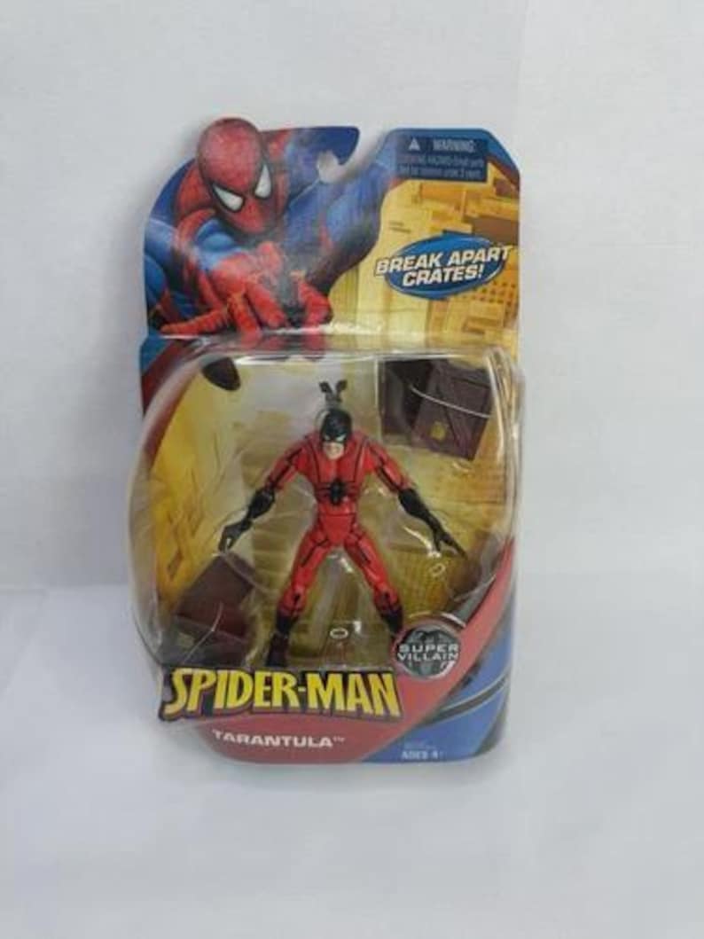 May include: A Spider-Man action figure of the character Tarantula, packaged in a blister pack. The figure is red and black, with a black mask. The packaging features Spider-Man artwork and the text "Break Apart Crates!" and "Super Villain."