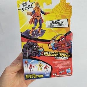 May include: A packaged action figure of the Hobgoblin from the Spider-Man series. The figure is on a yellow and red background with the text "Air Assault Hobgoblin" and "Fiercest Foes!" The figure is on a glider.