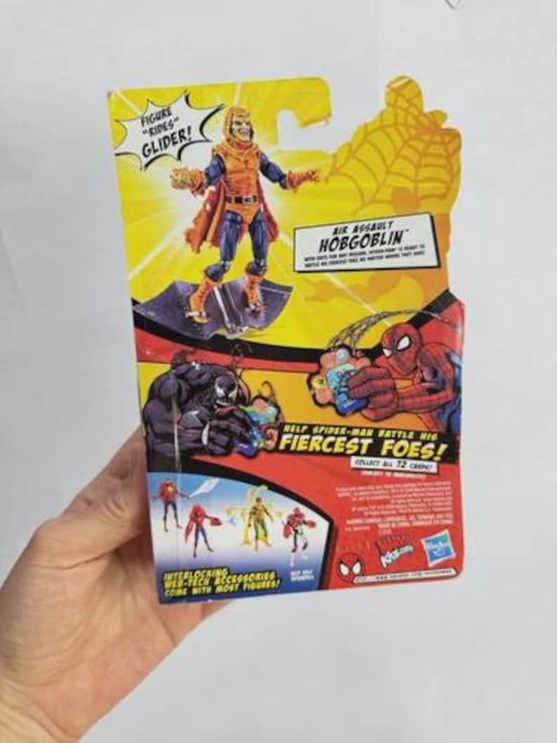 May include: A packaged action figure of the Hobgoblin from the Spider-Man series. The figure is on a yellow and red background with the text "Air Assault Hobgoblin" and "Fiercest Foes!" The figure is on a glider.