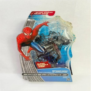 Peut inclure: Une figurine Spider-Man dans un emballage plastique. La figurine est rouge et bleue, avec un motif de toile d'araign&eacute;e. L'emballage comprend un autocollant &agrave; d&eacute;coller et le texte "Super-Posable Web!" et "Spider-Man 3".