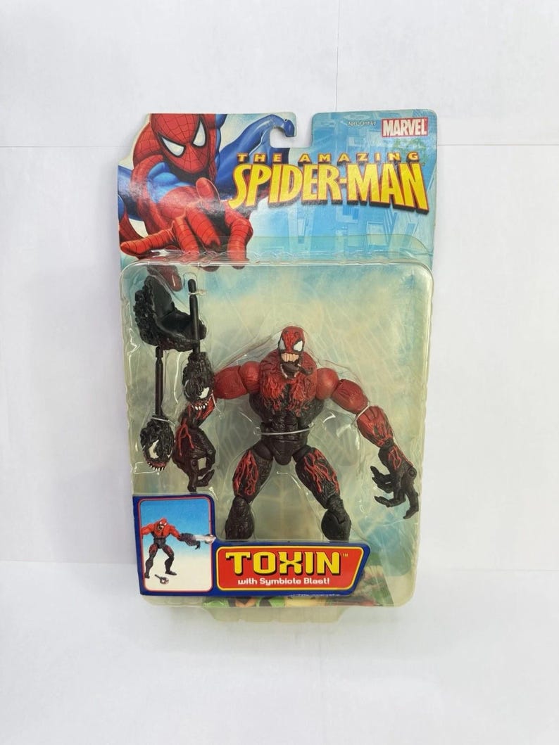 Puede incluir: Figura de acci&oacute;n empaquetada de Toxin de The Amazing Spider-Man. La figura es roja y negra con un accesorio de explosi&oacute;n simbionte. El embalaje presenta ilustraciones de Spider-Man y el logotipo de Marvel.