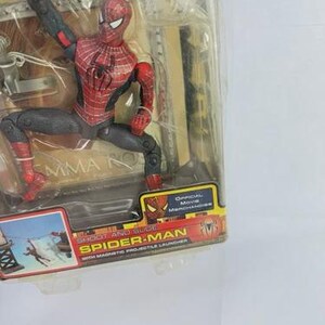 May include: Spider-Man action figure in a clear plastic package. The figure is red, black, and gray, with a detailed costume. The packaging includes the text "Spider-Man" and "Official Movie Merchandise."