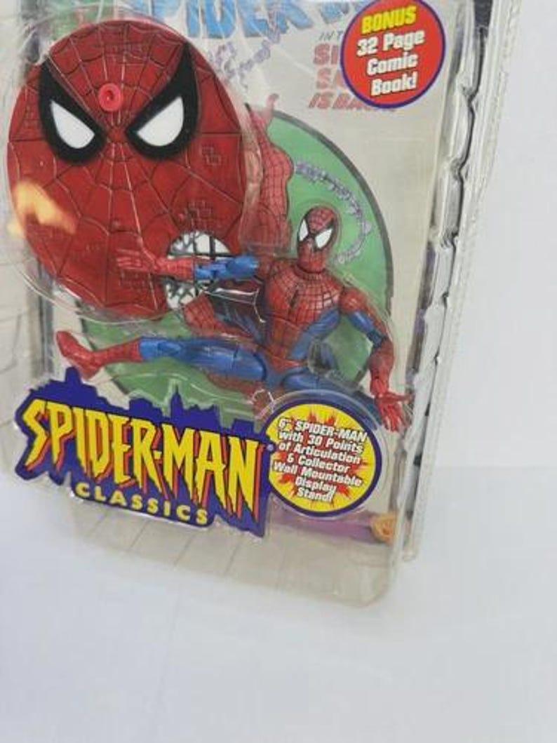 May include: Spider-Man Classics action figure in packaging. The figure is red and blue, with a web design. The packaging includes a bonus 32-page comic book and a collector wall mountable display stand.