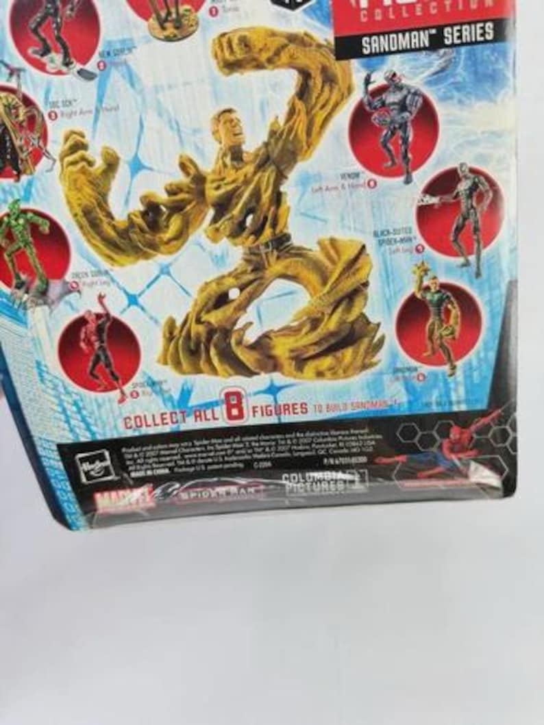 May include: A Sandman action figure from the Marvel Collection series. The figure is primarily tan and brown, with a detailed, textured design. The packaging features other figures and the text "COLLECT ALL 8 FIGURES TO BUILD SANDMAN".