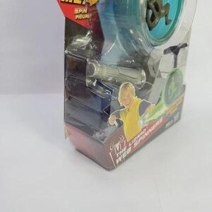 May include: A Spider-Man toy featuring a spinning figure in a clear plastic package. The package has the text "TRY ME!" and "SPIN FIGURE". The toy includes a small figure and a web spinner.